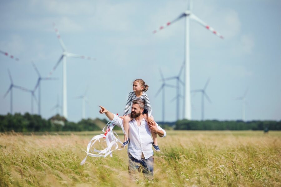 Vater und Tochter vor Windrädern als Symbol für das Ziel von nachhaltigem Bauen
