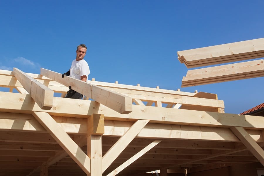 Mann bei der Errichtung eines Dachstuhls aus Holz