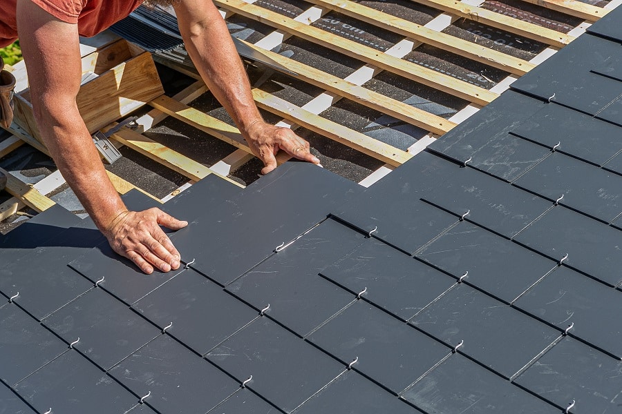 Handwerker deckt Dach mit Schieferplatten