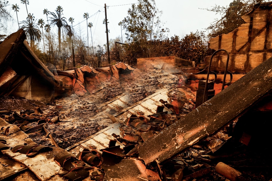 Burned remains of a home after a devastating urban wildfire, with smoldering debris and charred structures. The article 'Urban Wildfire Cleanup: Challenges, Lessons, and How Construction Can Build Resilient Communities' explores recovery efforts, sustainable rebuilding, and fire-resistant construction strategies