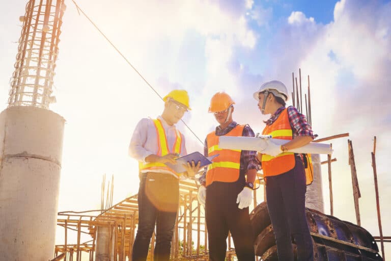 Construction workers reviewing digital blueprints on a jobsite, illustrating paperless workflow challenges and digital transformation in the AEC industry.