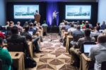 Attendees at a Bluebeam Unbound conference session watch a case study presentation in a packed room with laptops open, highlighting key sessions and industry insights.