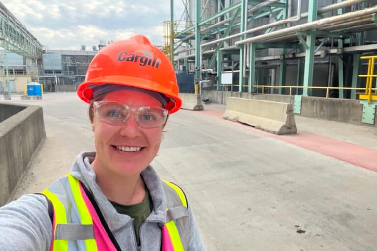 Mara Horn, construction manager at Cargill, smiles in a hard hat and safety gear while on-site at an industrial construction project, showcasing women’s leadership in the field.