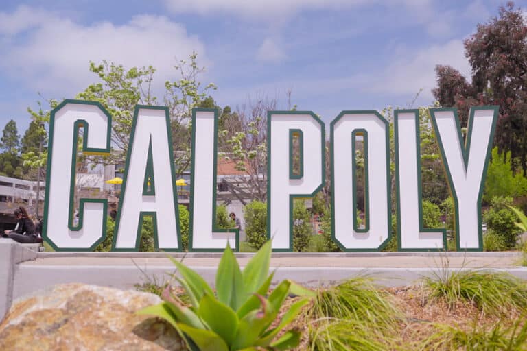 Large CAL POLY campus sign surrounded by greenery and blue sky, representing Cal Poly’s construction management program that embeds Bluebeam software into the curriculum to prepare students for digital workflows.