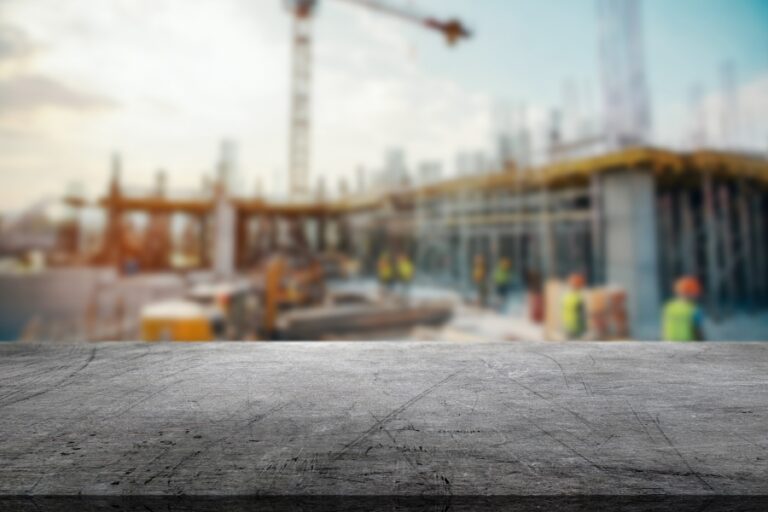 Autonomous construction equipment operating on a jobsite while a superintendent reviews digital drawings on a tablet.