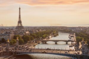 Panoramic view of Paris skyline with the Eiffel Tower and bridges over the Seine River, illustrating dense historic urban infrastructure where construction and renovation projects must adapt to tight space, heritage preservation and modern sustainability regulations.