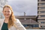 Professional headshot of Brittany Harris standing outdoors in an urban setting, featured in an interview about scaling construction technology startup Qflow beyond sustainability and improving construction materials and waste data management.
