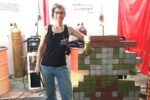 Welder Shanen Aranmor stands beside a pixel-art sculpture welded from painted steel blocks at her Weld Like a Girl shop in Yuma, Arizona.