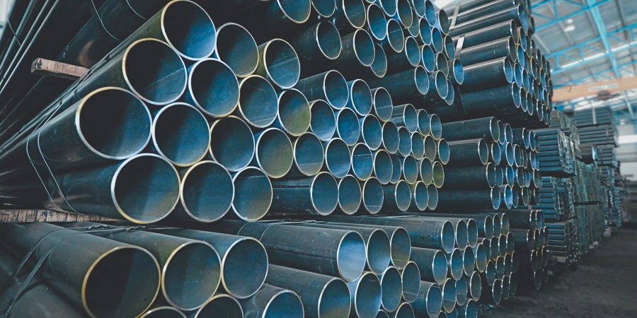 Steel pipes stacked in a warehouse, representing the construction industry's reliance on steel materials. The image reflects the impact of the blocked U.S. Steel merger on construction projects in 2025, highlighting the challenges posed by rising steel costs and supply chain disruptions in the industry.