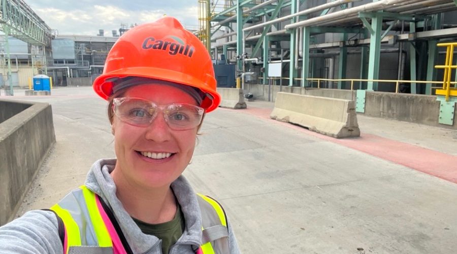 Mara Horn, construction manager at Cargill, smiles in a hard hat and safety gear while on-site at an industrial construction project, showcasing women’s leadership in the field.