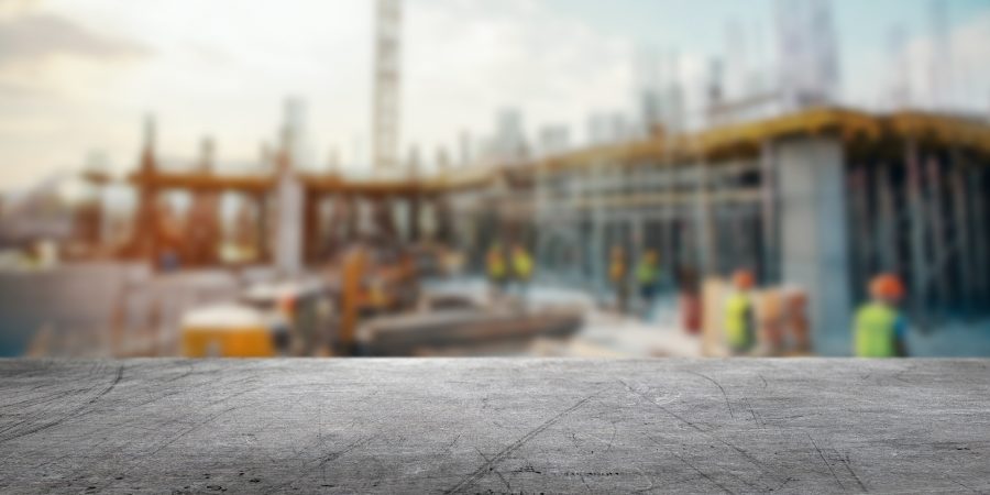 Autonomous construction equipment operating on a jobsite while a superintendent reviews digital drawings on a tablet.