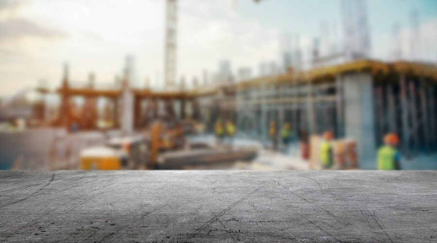 Autonomous construction equipment operating on a jobsite while a superintendent reviews digital drawings on a tablet.