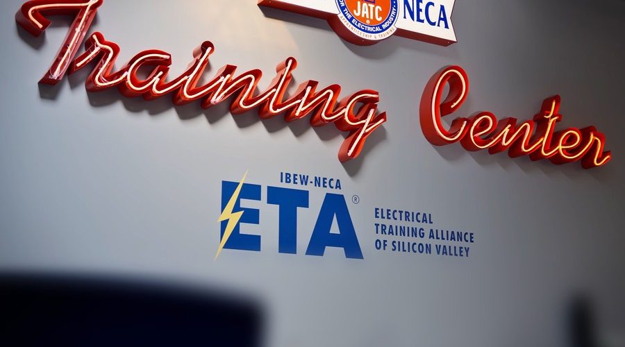Red neon "Training Center" sign above the IBEW-NECA Electrical Training Alliance of Silicon Valley logo at ETASV in Milpitas, California.