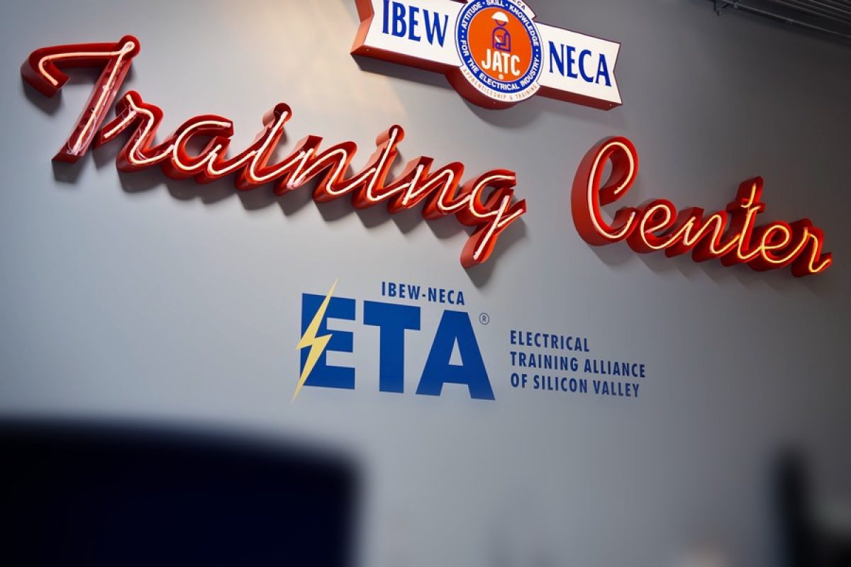 Red neon "Training Center" sign above the IBEW-NECA Electrical Training Alliance of Silicon Valley logo at ETASV in Milpitas, California.