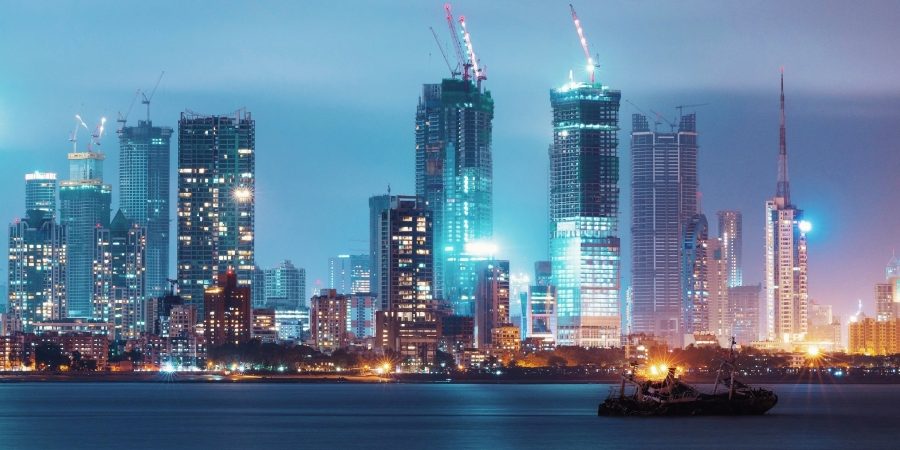 Mumbai skyline with high-rise towers and construction cranes at night, illustrating rapid urban development and infrastructure growth.