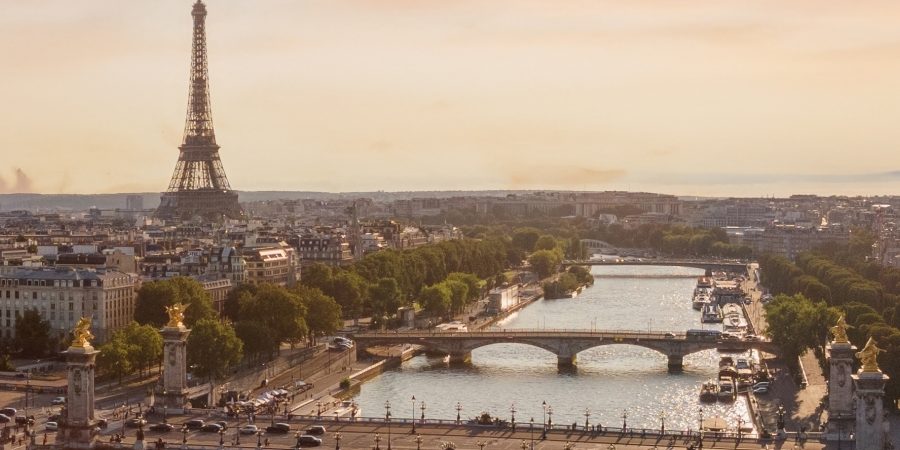 Panoramic view of Paris skyline with the Eiffel Tower and bridges over the Seine River, illustrating dense historic urban infrastructure where construction and renovation projects must adapt to tight space, heritage preservation and modern sustainability regulations.