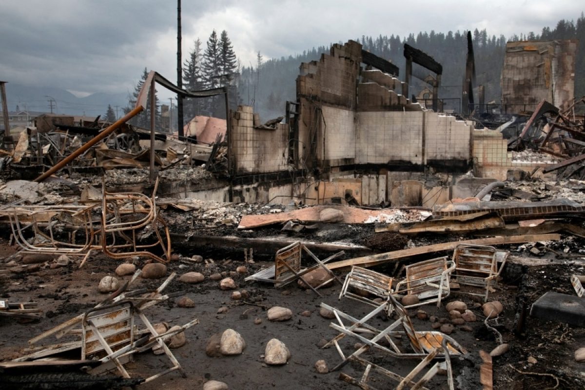 Burned residential structures and debris after a wildfire, showing cleared lots and stalled rebuilding in an urban neighborhood during post-fire recovery.