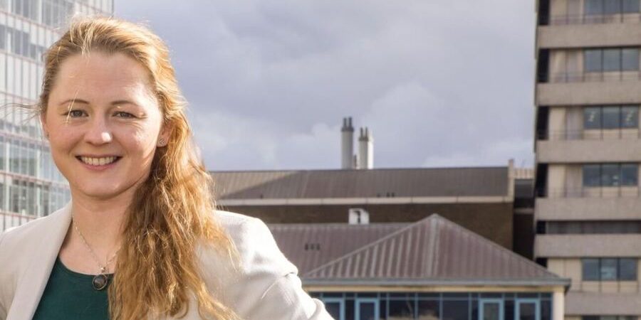 Professional headshot of Brittany Harris standing outdoors in an urban setting, featured in an interview about scaling construction technology startup Qflow beyond sustainability and improving construction materials and waste data management.