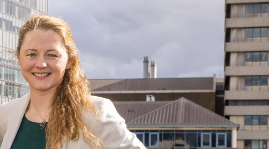 Professional headshot of Brittany Harris standing outdoors in an urban setting, featured in an interview about scaling construction technology startup Qflow beyond sustainability and improving construction materials and waste data management.