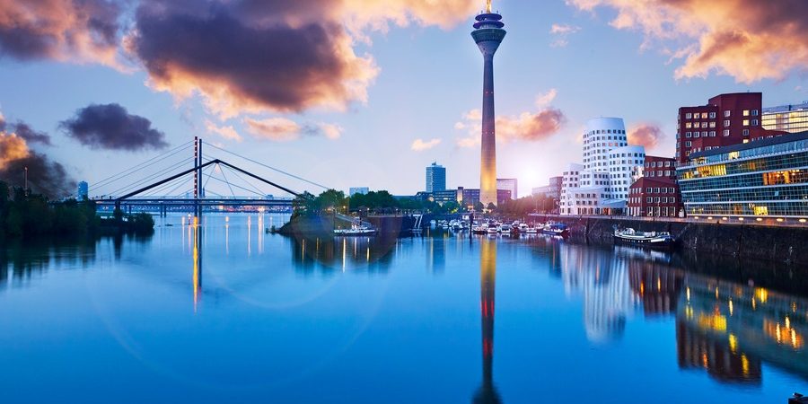 Düsseldorf skyline at sunset with the Rheinturm tower and Medienhafen Gehry buildings reflected in the harbor