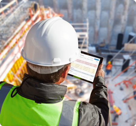 Construction worker looks at tablet while overlooking jobsite